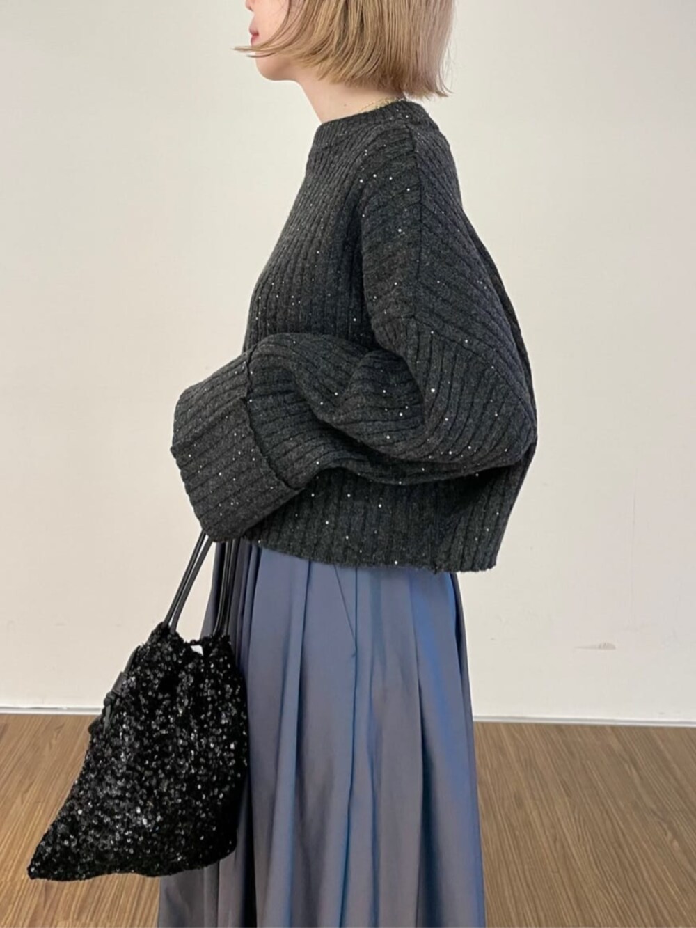 ブラック系のショルダーバッグ、ブルー系のスカート、グレー系のニット/セーターを着用したレディースの秋コーディネートの4枚目の写真