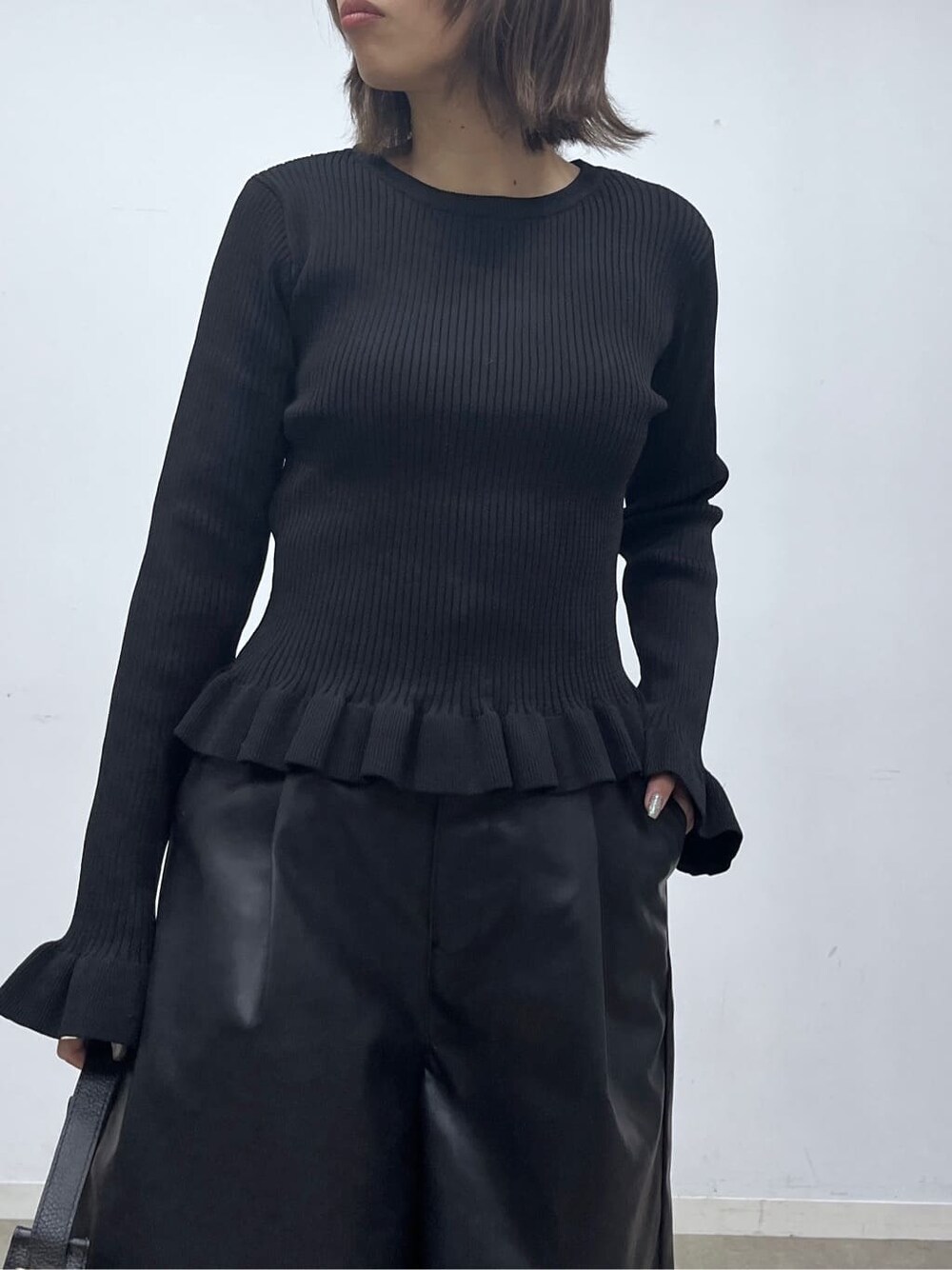 ブラック系のニット/セーター、ブラック系のその他パンツ、ブラック系のハンドバッグを着用したレディースの秋コーディネートの6枚目の写真