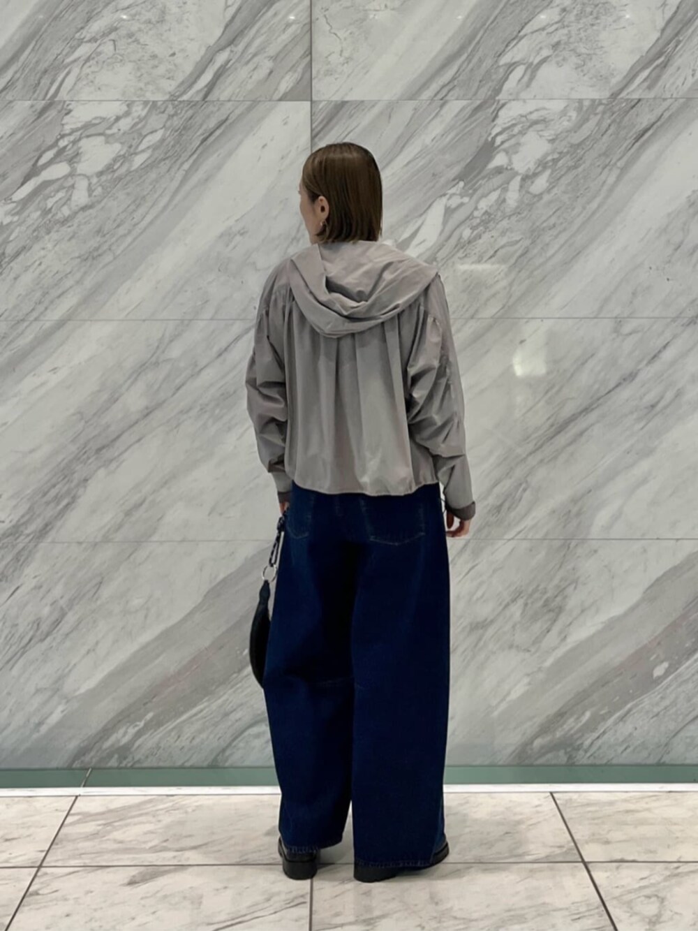 ブルー系のデニムパンツ、ブラック系のベスト、グレー系のブルゾンを着用したレディースの冬コーディネートの5枚目の写真