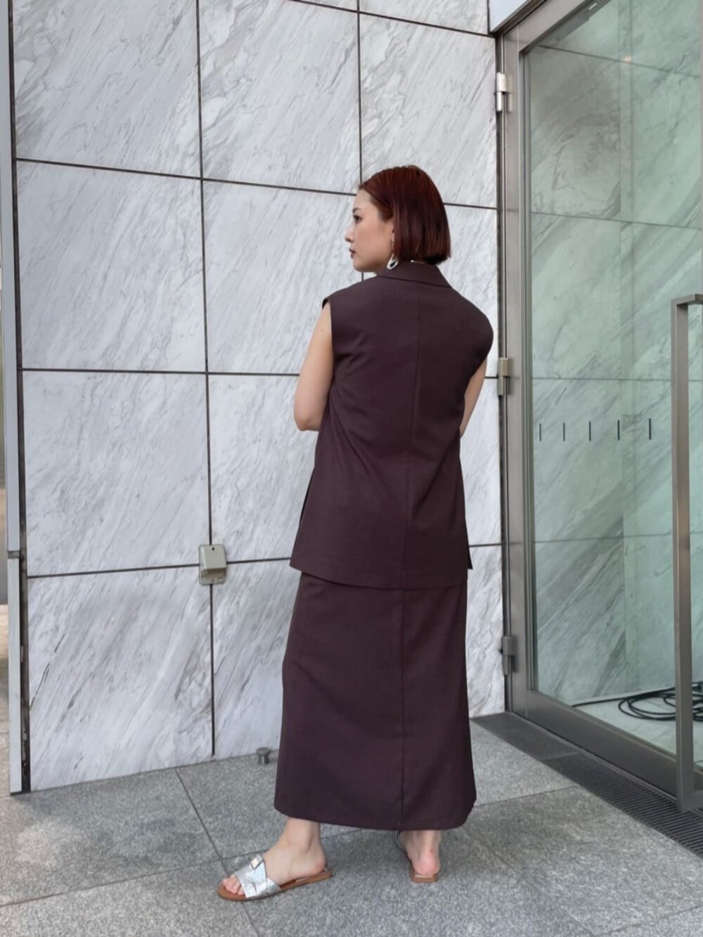 シルバー系のタンクトップ、ブラウン系のベスト、ブラウン系のスカートを着用したレディースの夏コーディネートの3枚目の写真