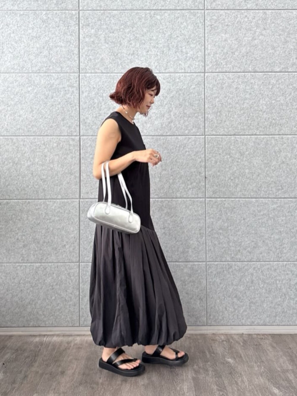 ブラック系のサンダル、シルバー系のハンドバッグ、ブラック系のワンピースを着用したレディースの夏コーディネートの4枚目の写真
