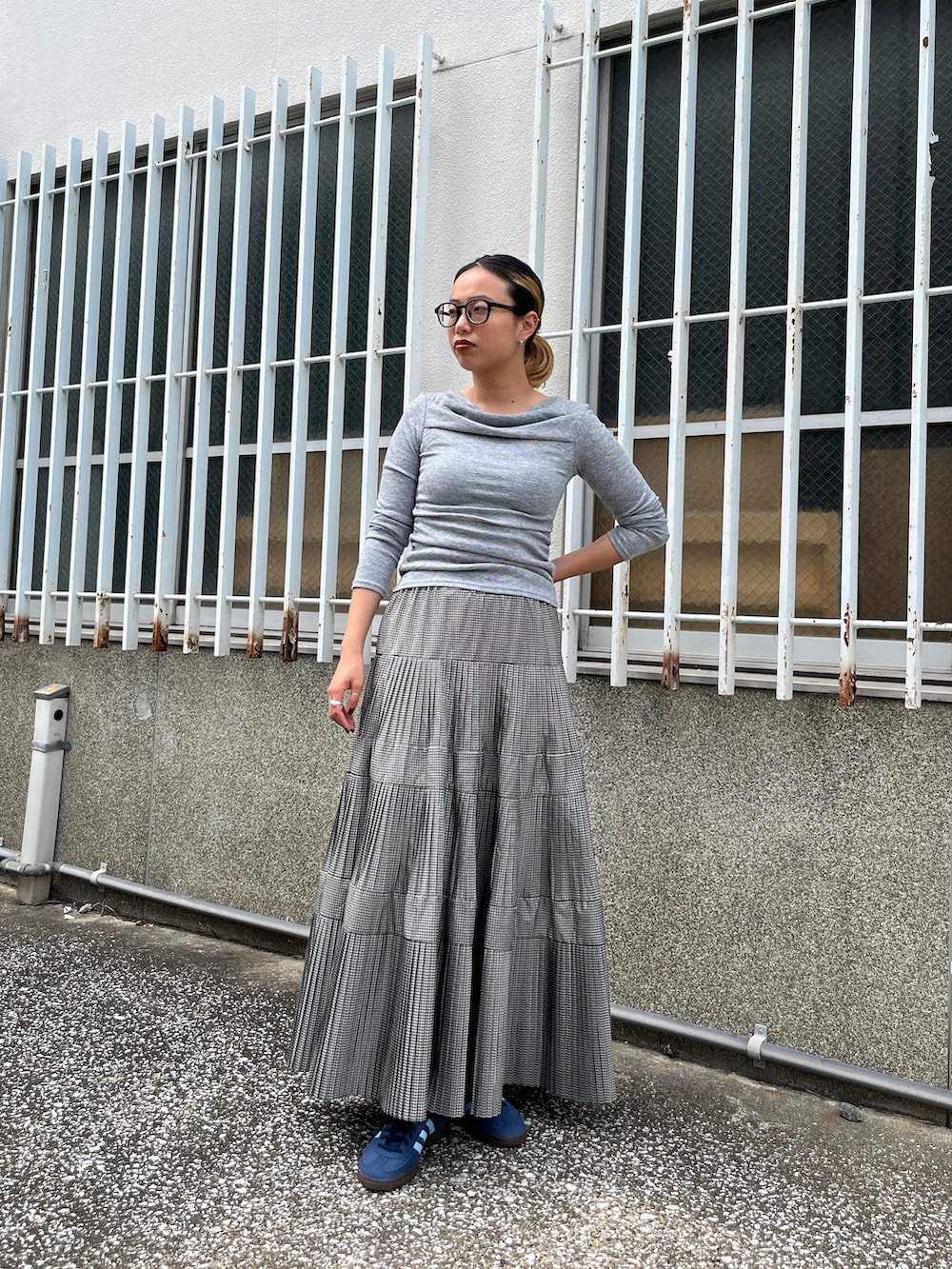 グレー系のTシャツ/カットソー、ブラック系のスカート、ブルー系のスニーカーを着用したレディースの秋コーディネートの10枚目の写真