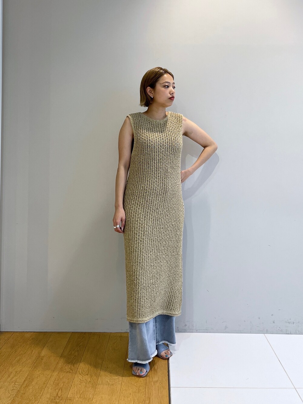 イエロー系のワンピース、ブルー系のデニムパンツ、ブルー系のサンダルを着用したレディースの春コーディネートの9枚目の写真