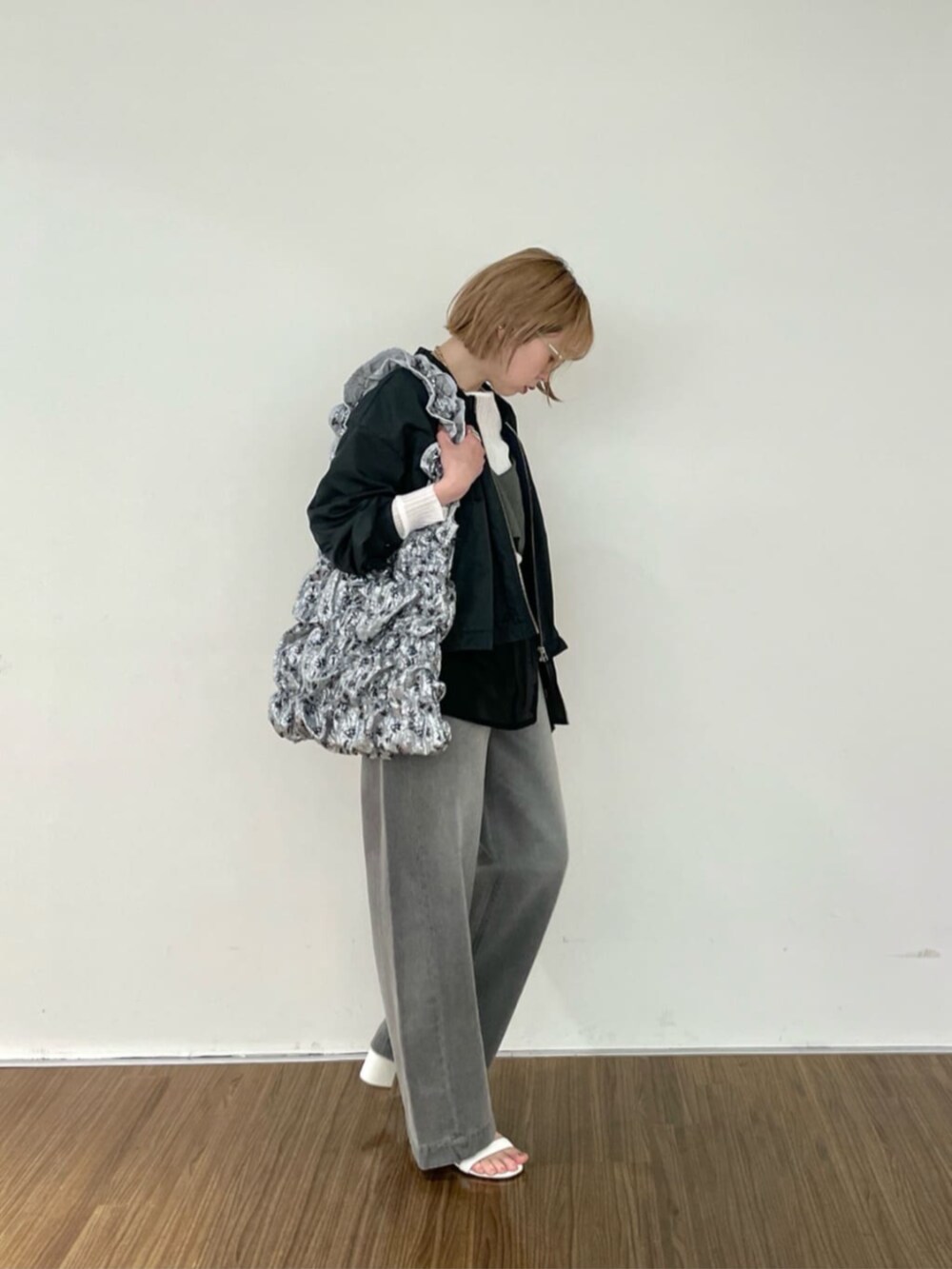 グレー系のデニムパンツ、ホワイト系のニット/セーター、グレー系のブルゾンを着用したレディースの春コーディネートの3枚目の写真