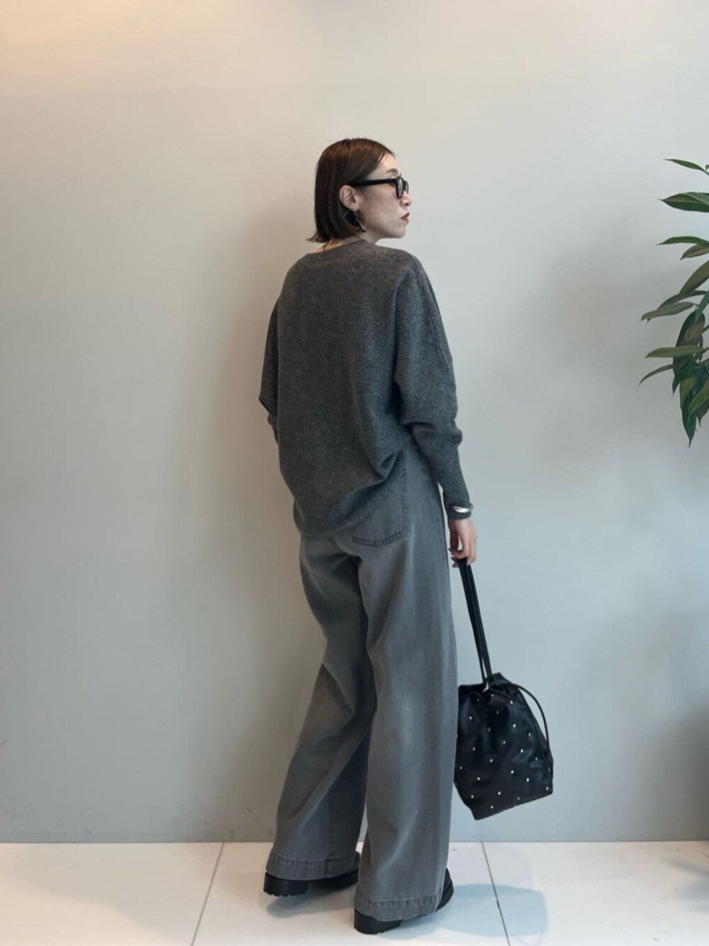 ブラック系のハンドバッグ、グレー系のデニムパンツ、グレー系のニット/セーターを着用したレディースの秋コーディネートの4枚目の写真