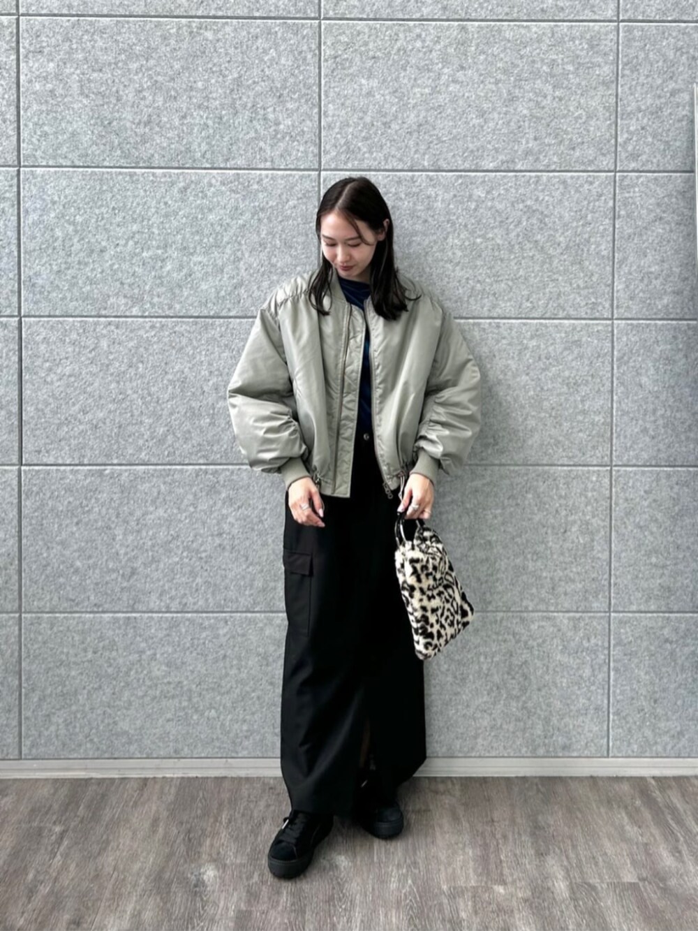 ブラウン系のハンドバッグ、ブラック系のスカート、ブルー系のTシャツ/カットソーを着用したレディースの秋コーディネートの3枚目の写真