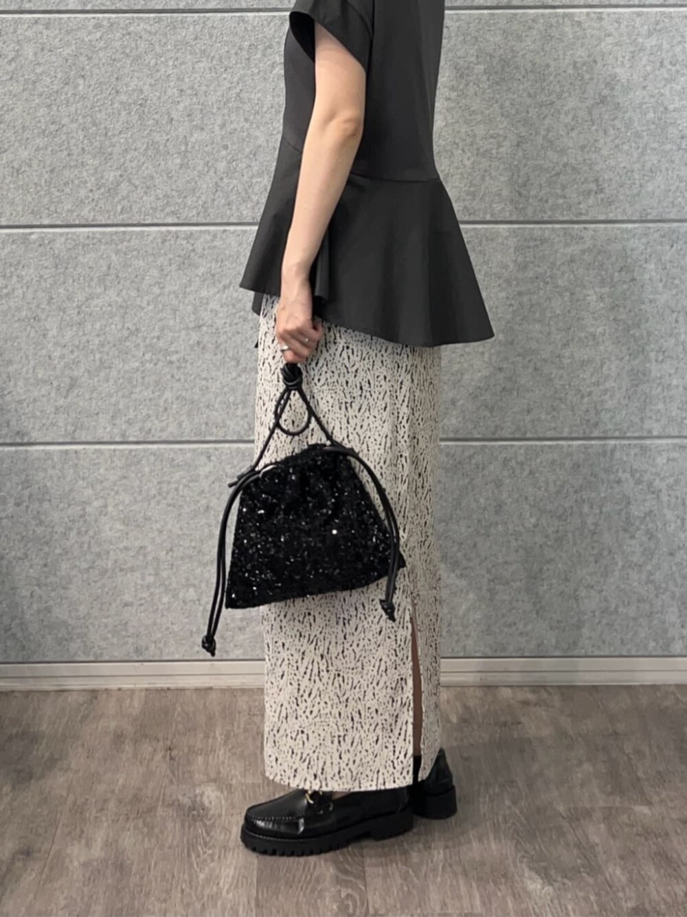 ブラック系のショルダーバッグ、グレー系のTシャツ/カットソー、ホワイト系のスカートを着用したレディースの秋コーディネートの3枚目の写真