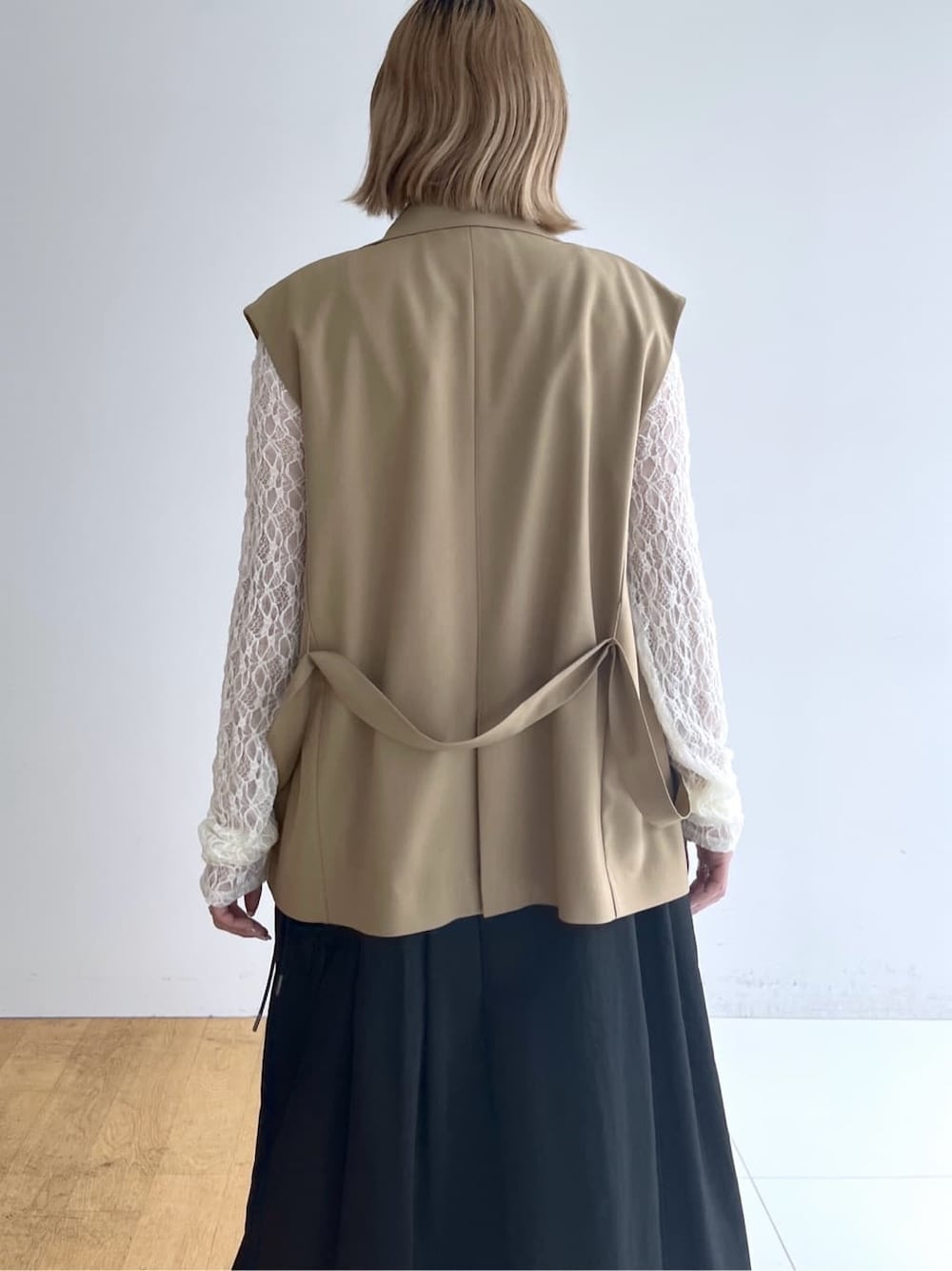イエロー系のベスト、ホワイト系のTシャツ/カットソー、グレー系のスカートを着用したレディースの春コーディネートの6枚目の写真