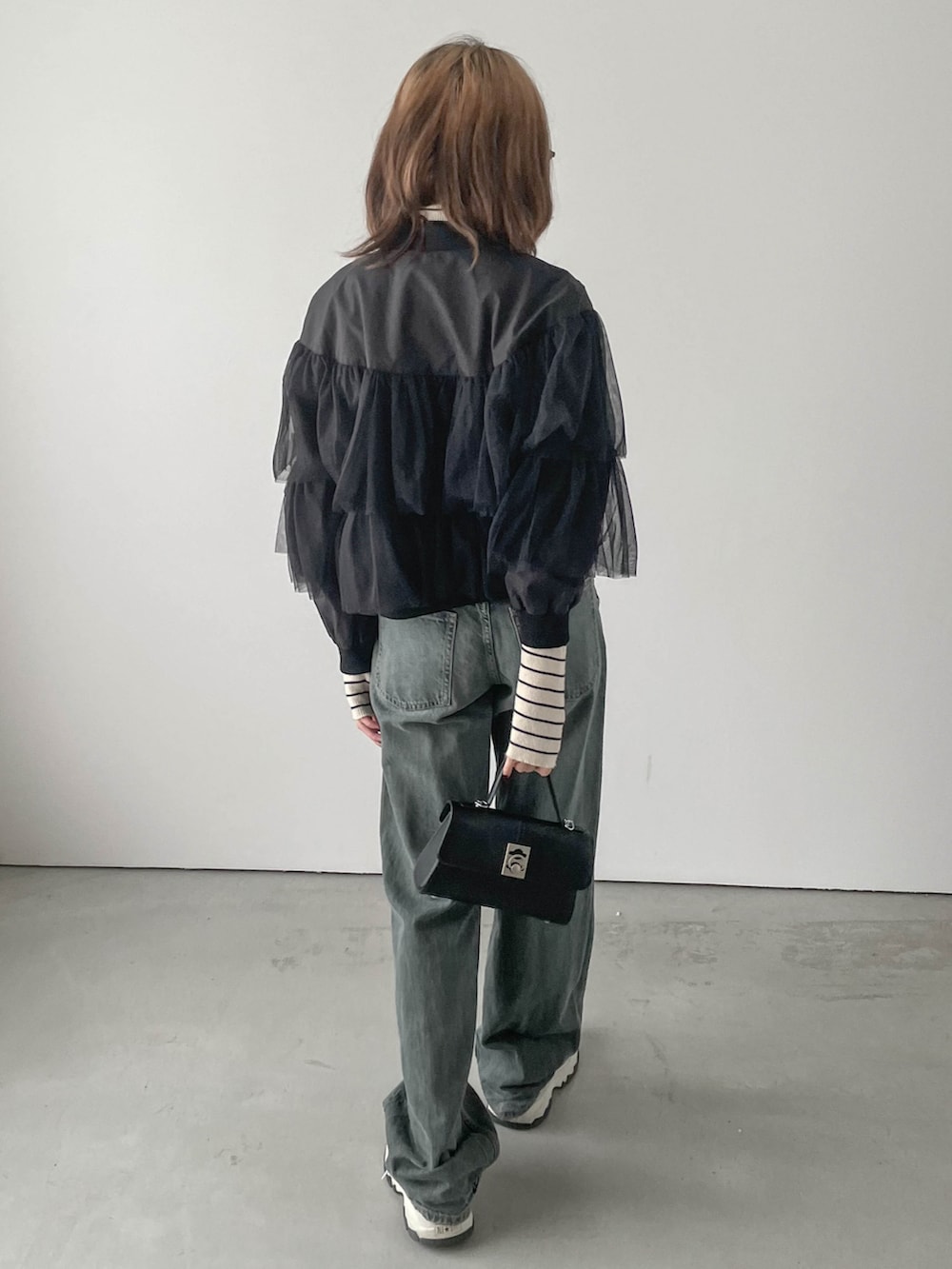 ブラック系のスニーカー、ブルー系のデニムパンツ、ブラック系のブルゾンを着用したレディースの秋コーディネートの2枚目の写真