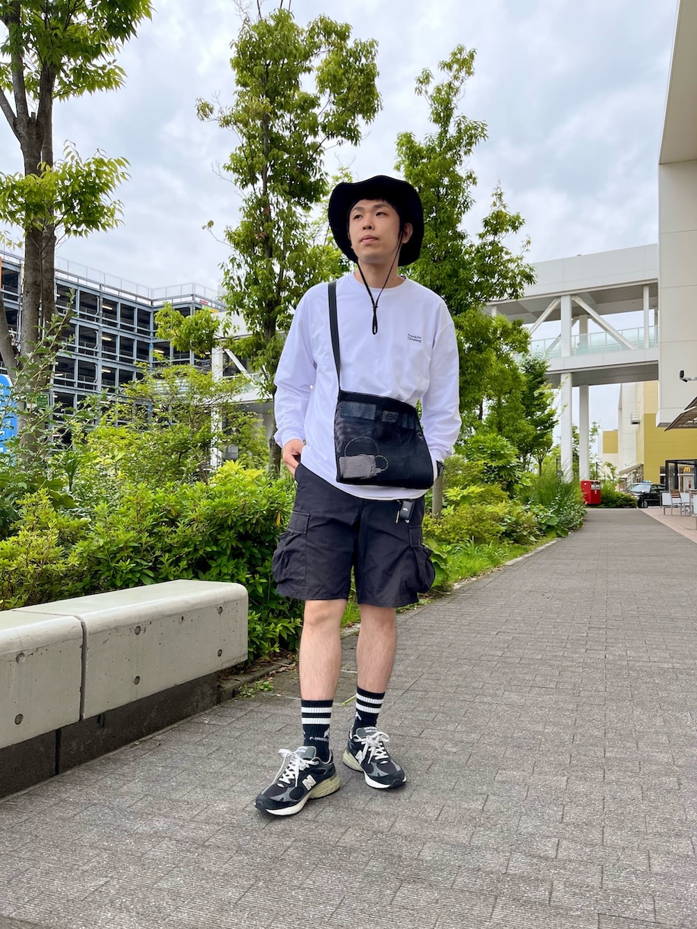 ホワイト系のTシャツ/カットソー、ブラック系のショルダーバッグ、ブラック系のカーゴパンツを着用したメンズの夏コーディネートの2枚目の写真