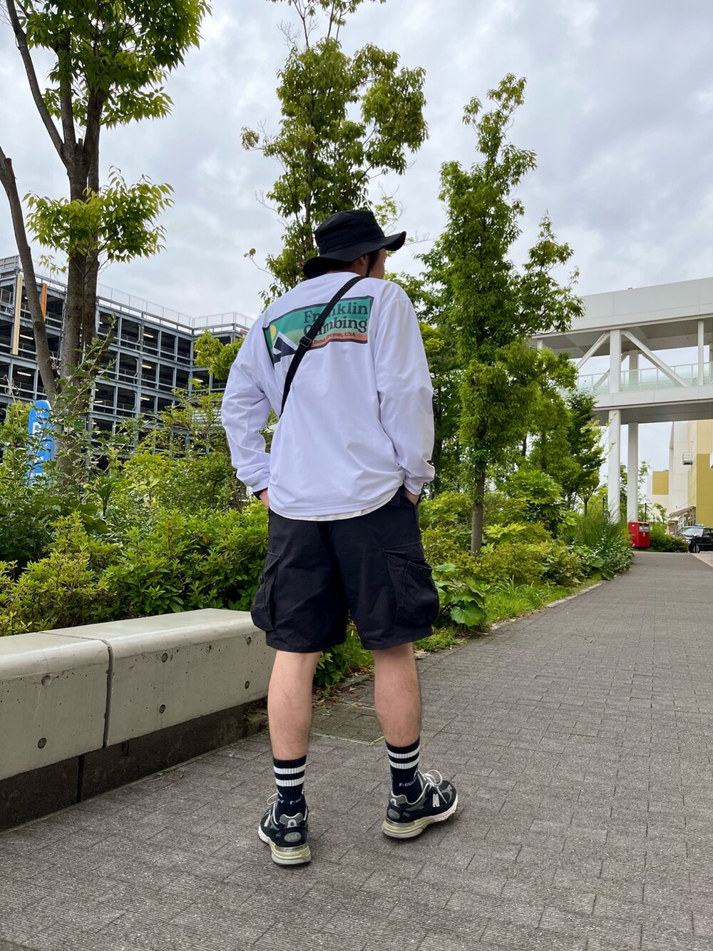 ホワイト系のTシャツ/カットソー、ブラック系のショルダーバッグ、ブラック系のカーゴパンツを着用したメンズの夏コーディネートの3枚目の写真