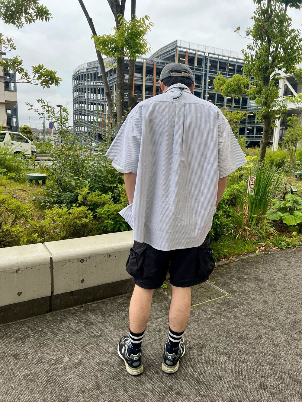 ブラック系のスニーカー、ブラック系のカーゴパンツ、ブラック系のショルダーバッグを着用したメンズの夏コーディネートの3枚目の写真