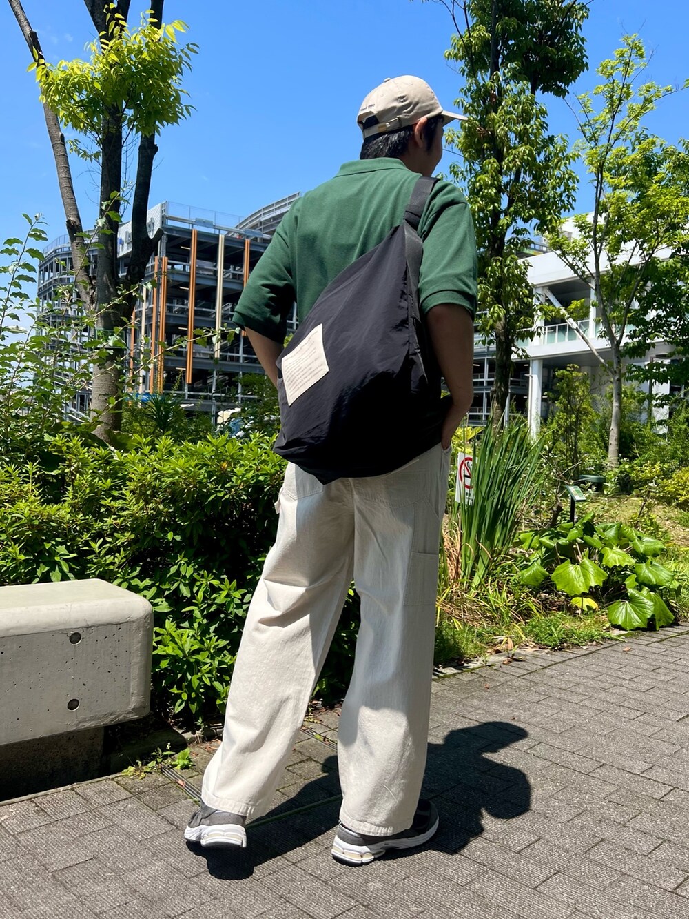 グリーン系のポロシャツ、ブラック系のショルダーバッグ、ホワイト系のデニムパンツを着用したメンズの夏コーディネートの2枚目の写真