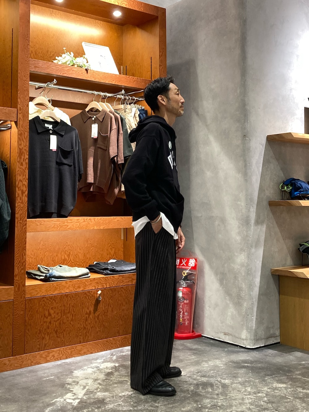 ブラック系のパーカー、ブラック系のスラックス、ホワイト系のTシャツ/カットソーを着用したメンズの秋コーディネートの2枚目の写真