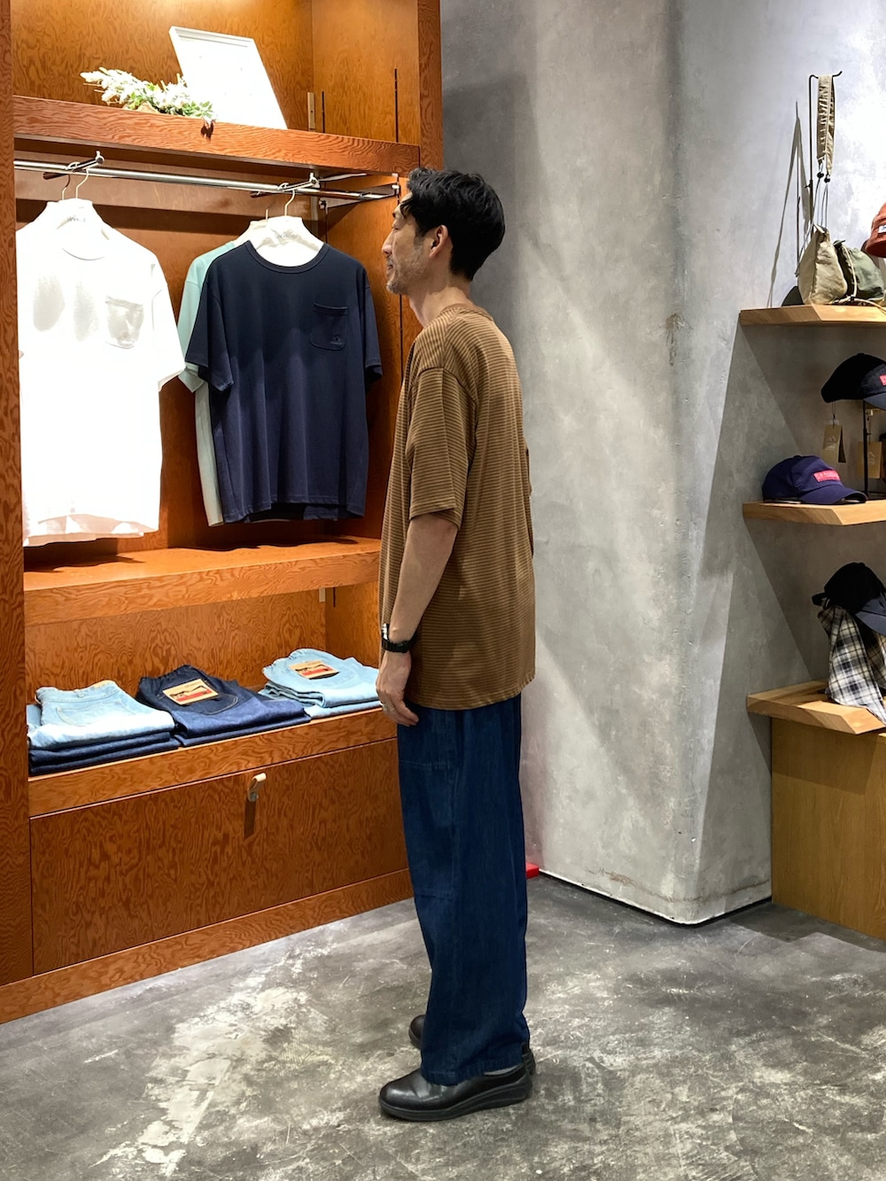 ブルー系のデニムパンツ、ブラウン系のTシャツ/カットソーを着用したメンズの夏コーディネートの2枚目の写真