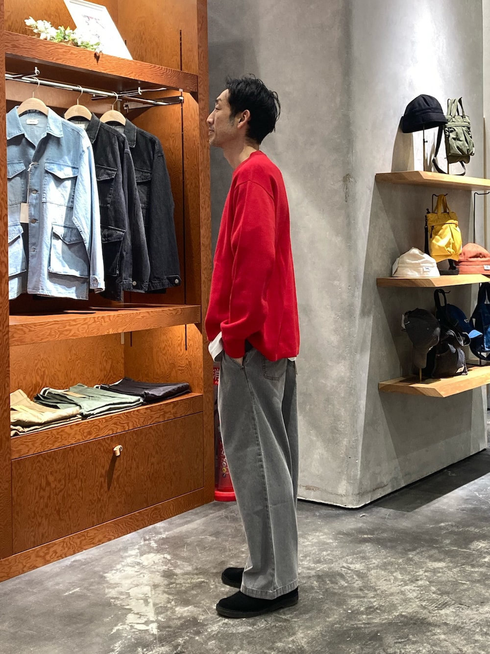 レッド系のニット/セーター、グレー系のデニムパンツを着用したメンズの春コーディネートの2枚目の写真