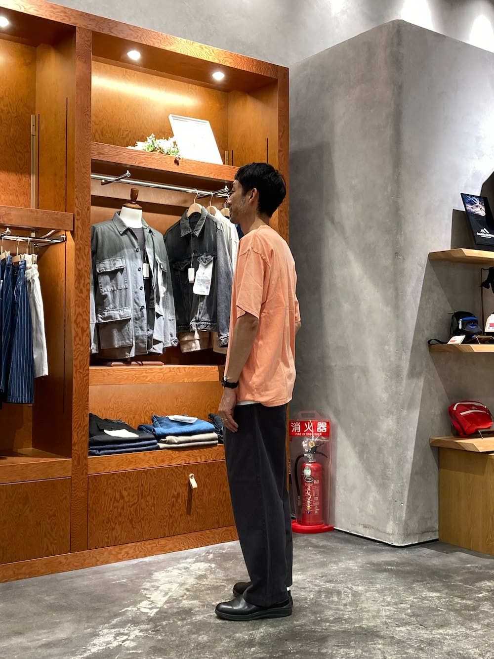 オレンジ系のTシャツ/カットソー、グレー系のチノパンツを着用したメンズの夏コーディネートの2枚目の写真