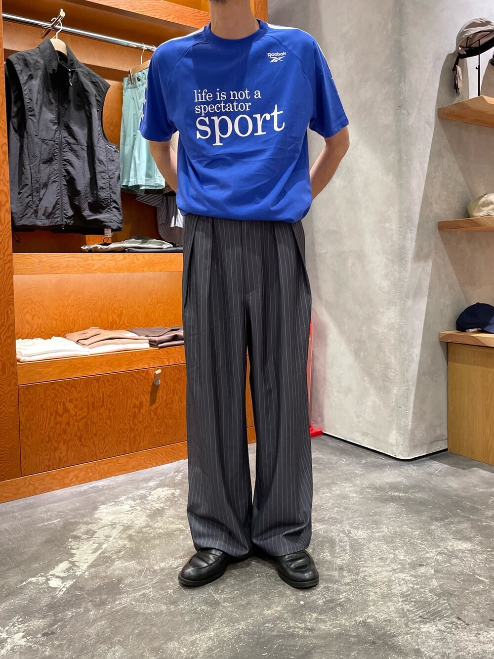 ブルー系のTシャツ/カットソー、グレー系のスラックスを着用したメンズの夏コーディネートの2枚目の写真