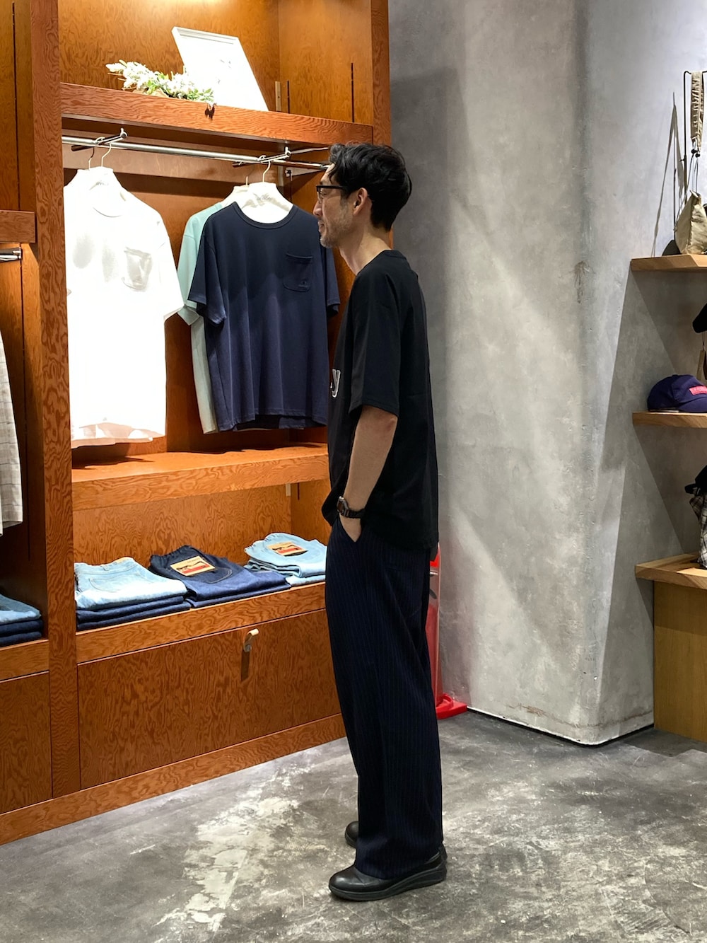 ブルー系のスラックス、ブラック系のTシャツ/カットソー、ブラック系のサングラスを着用したメンズの夏コーディネートの2枚目の写真