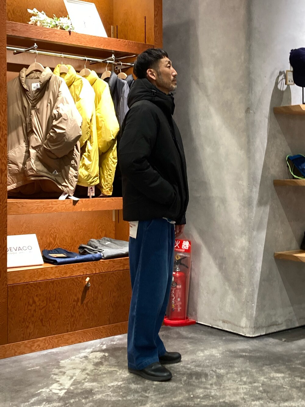 ブルー系のニット/セーター、ブルー系のデニムパンツ、ブラック系のダウンジャケット/コートを着用したメンズの冬コーディネートの2枚目の写真