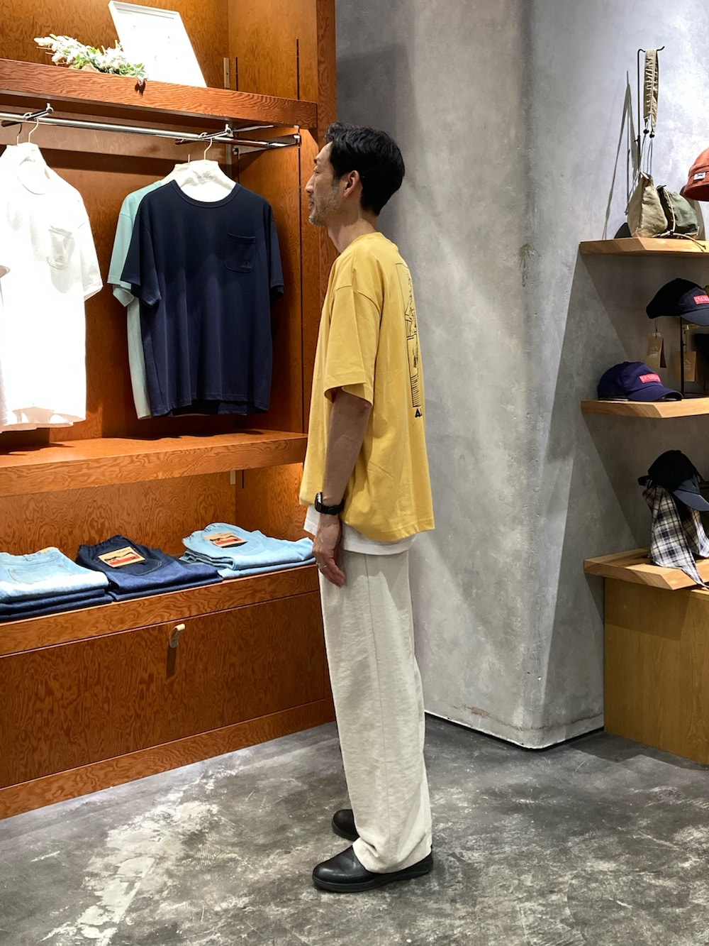 ホワイト系のスラックス、イエロー系のTシャツ/カットソーを着用したメンズの夏コーディネートの2枚目の写真