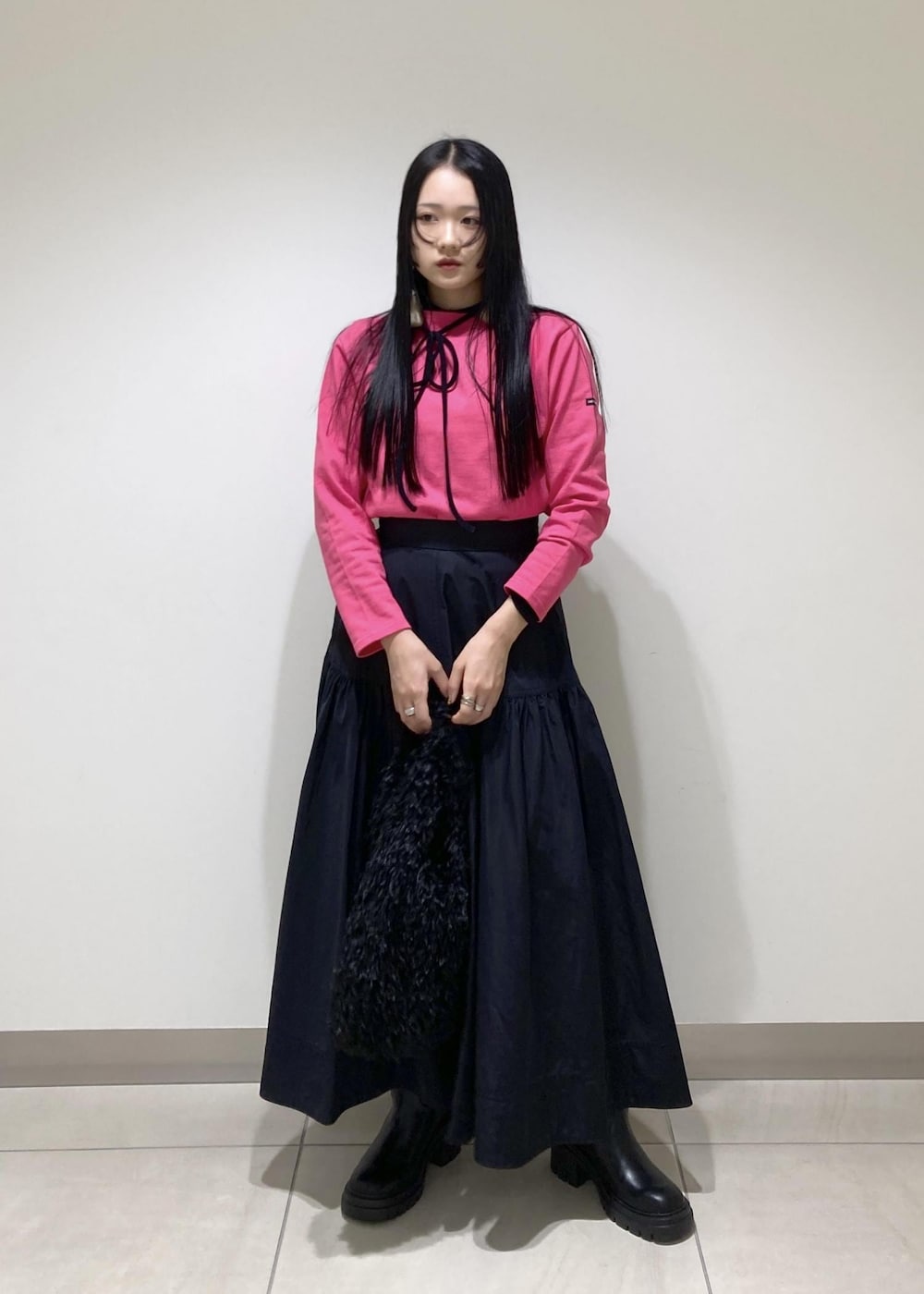 ブラック系のブーツ、ブラック系のスカート、ブラック系のハンドバッグを着用したレディースの秋コーディネートの2枚目の写真