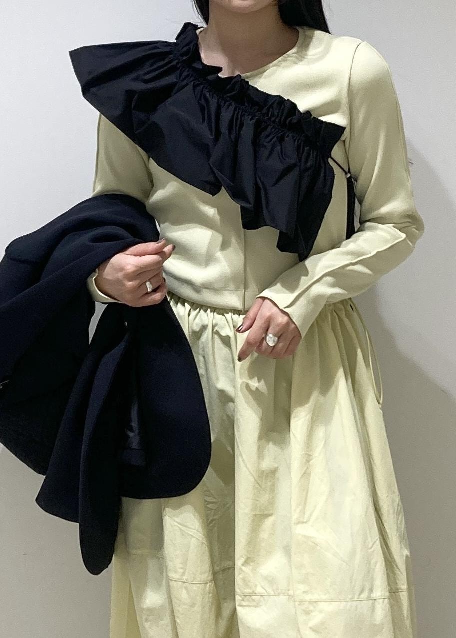 ブラック系のハンドバッグ、イエロー系のワンピース、ブラック系のワンピースを着用したレディースの冬コーディネートの6枚目の写真