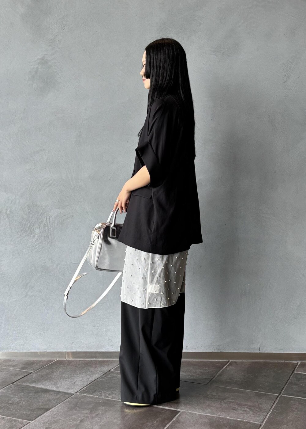 シルバー系のボストンバッグ、ブラック系のその他アウター、ブラック系のスラックスを着用したレディースの春コーディネートの4枚目の写真