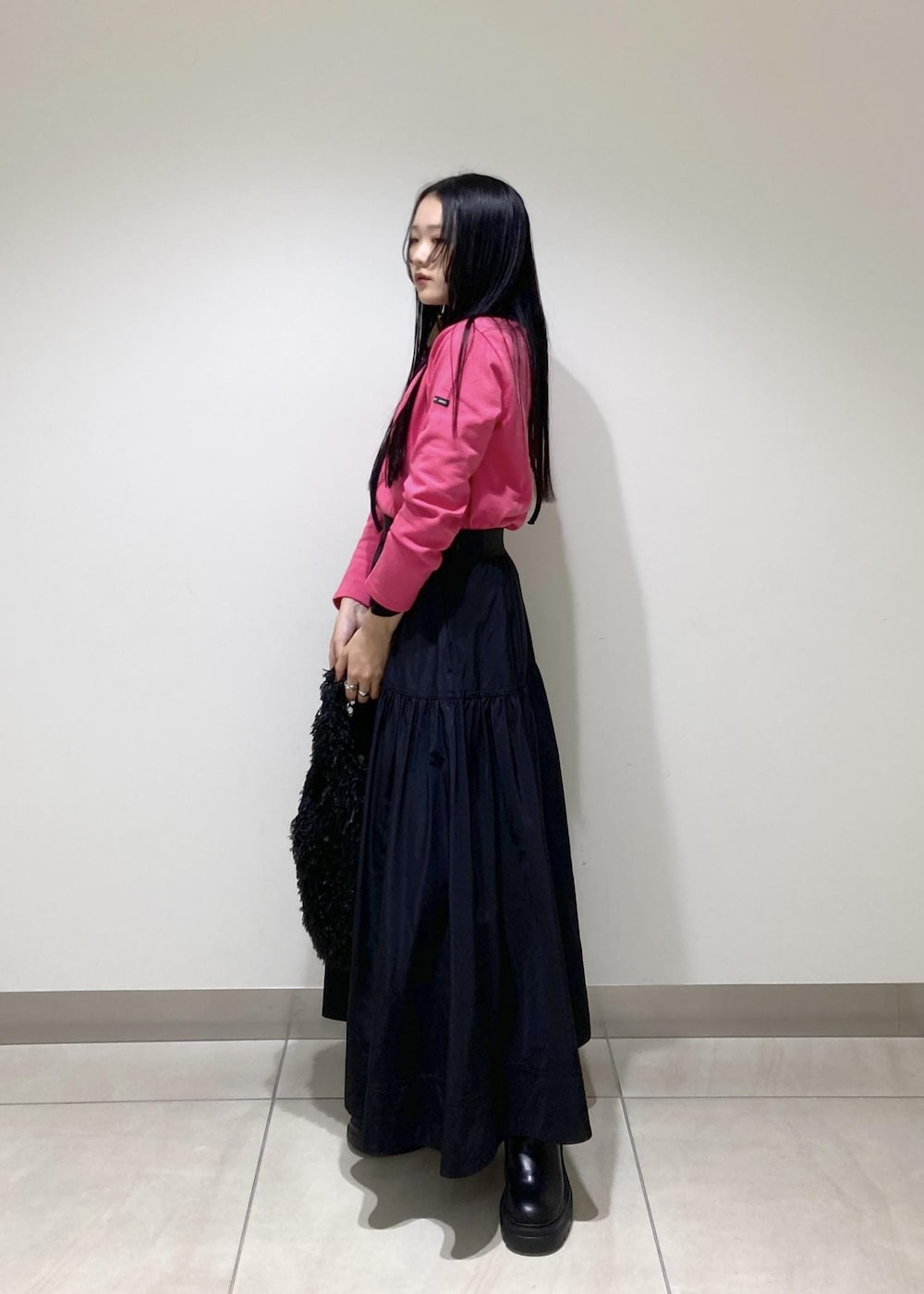 ブラック系のブーツ、ブラック系のスカート、ブラック系のハンドバッグを着用したレディースの秋コーディネートの3枚目の写真