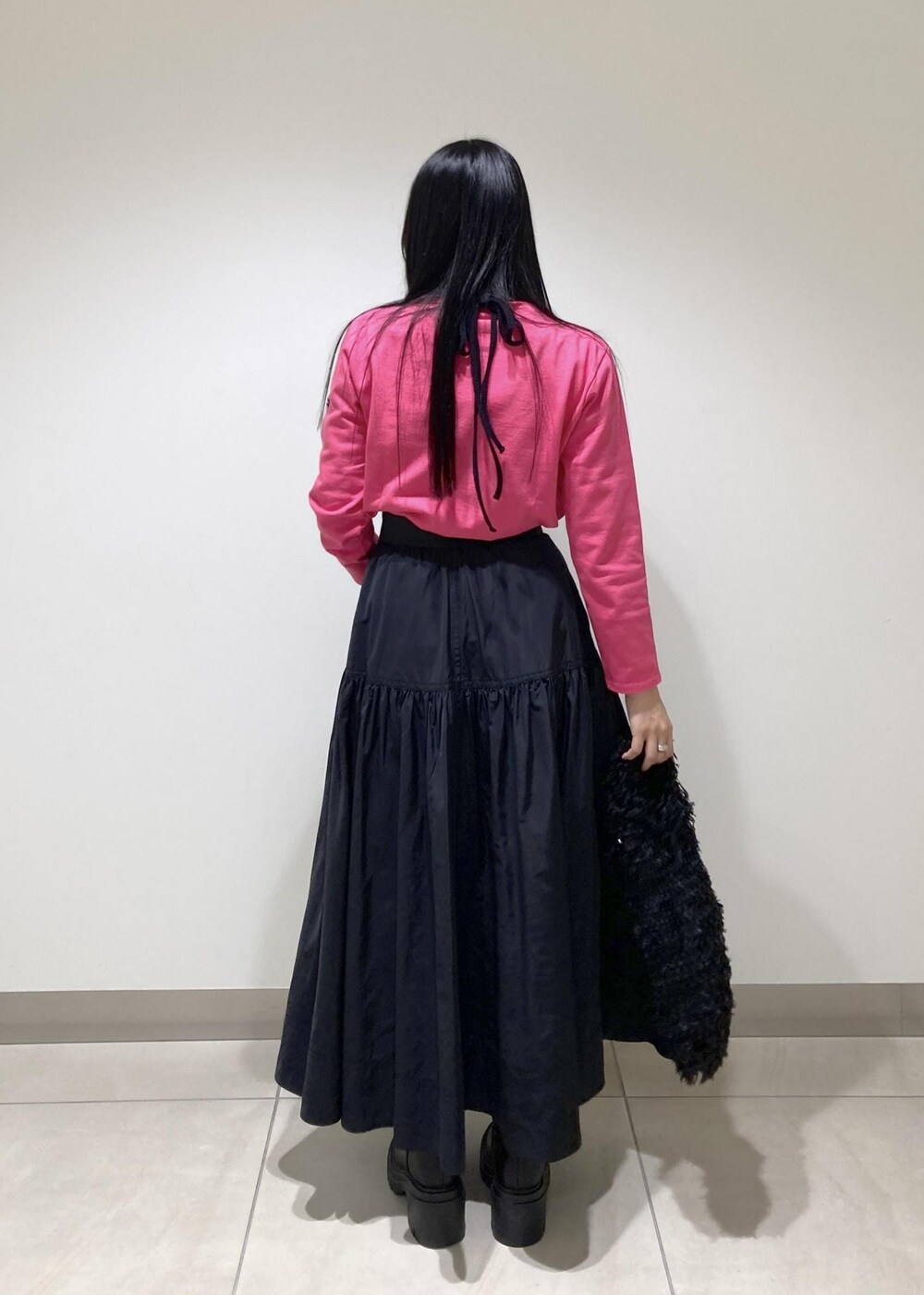 ブラック系のブーツ、ブラック系のスカート、ブラック系のハンドバッグを着用したレディースの秋コーディネートの5枚目の写真