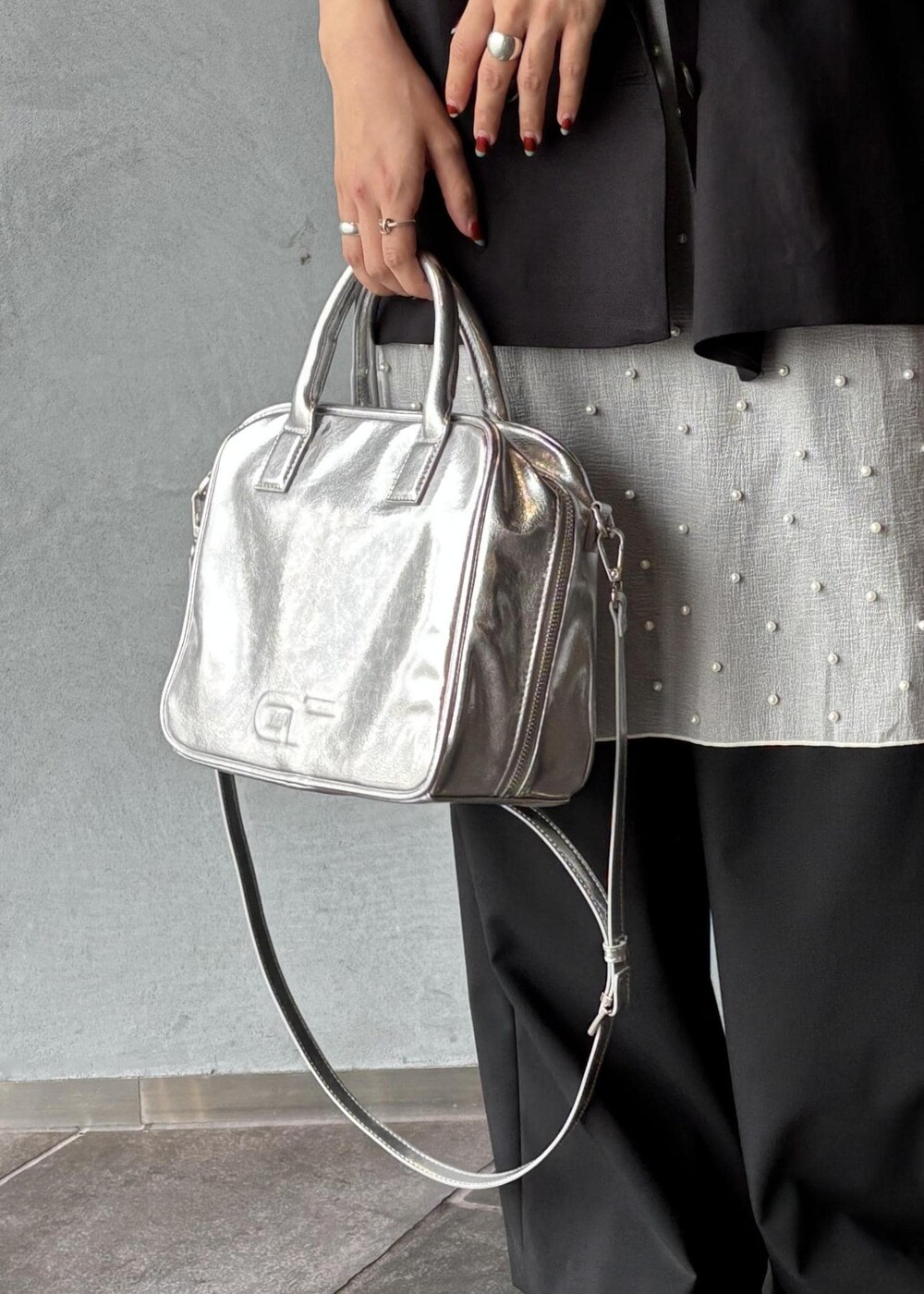 シルバー系のボストンバッグ、ブラック系のその他アウター、ブラック系のスラックスを着用したレディースの春コーディネートの9枚目の写真