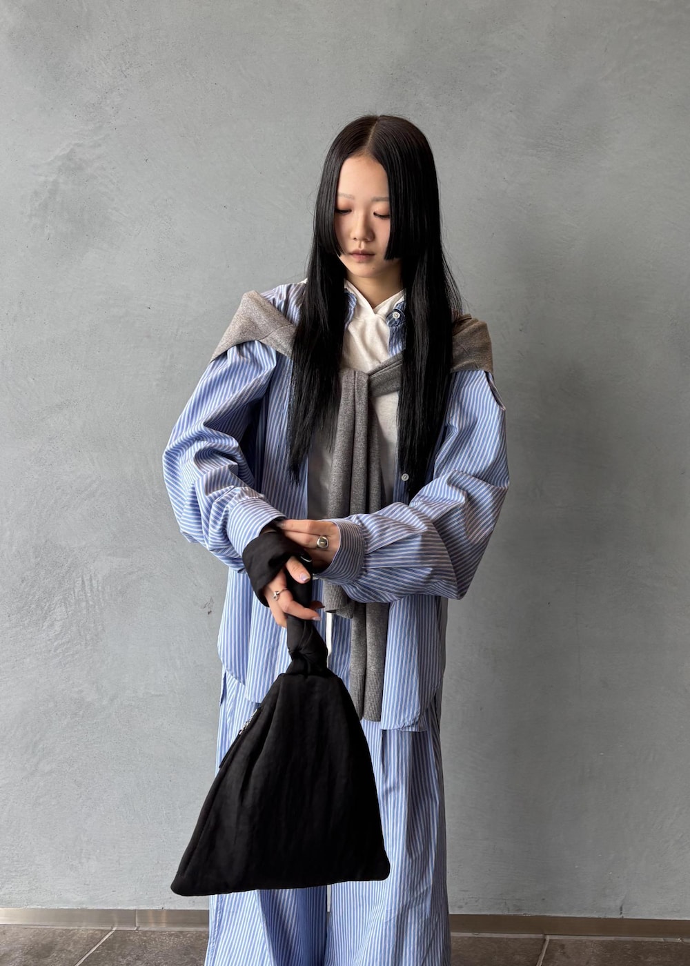 ブラック系のサンダル、グレー系のニット/セーター、ブラック系のハンドバッグを着用したレディースの秋コーディネートの6枚目の写真