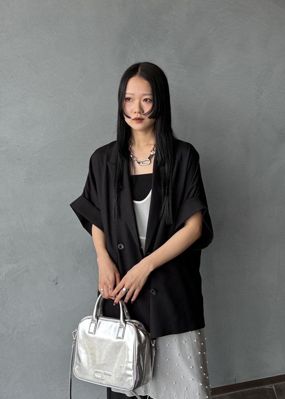 シルバー系のボストンバッグ、ブラック系のその他アウター、ブラック系のスラックスを着用したレディースの春コーディネートの7枚目の写真