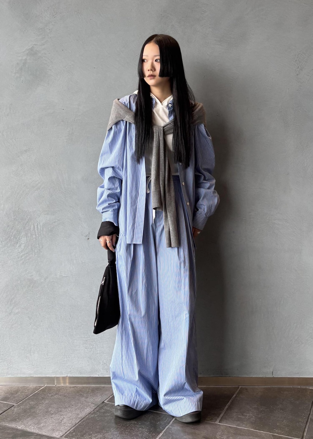 ブラック系のサンダル、グレー系のニット/セーター、ブラック系のハンドバッグを着用したレディースの秋コーディネートの2枚目の写真