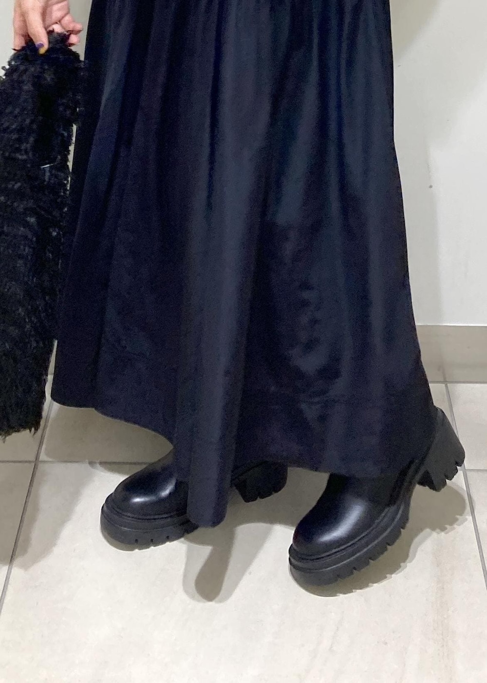 ブラック系のブーツ、ブラック系のスカート、ブラック系のハンドバッグを着用したレディースの秋コーディネートの8枚目の写真