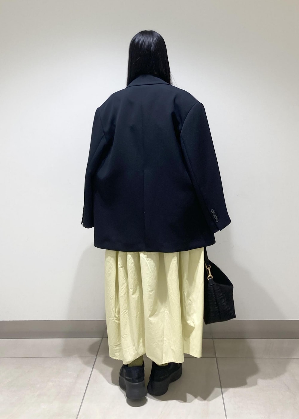 ブラック系のハンドバッグ、イエロー系のワンピース、ブラック系のワンピースを着用したレディースの冬コーディネートの4枚目の写真