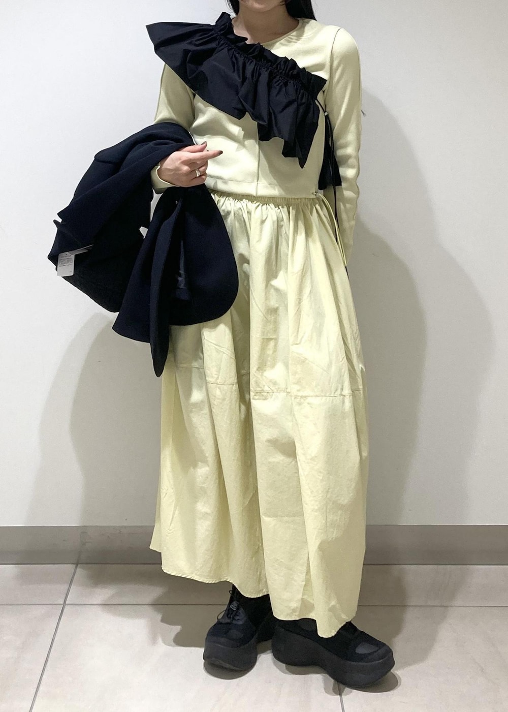 ブラック系のハンドバッグ、イエロー系のワンピース、ブラック系のワンピースを着用したレディースの冬コーディネートの5枚目の写真