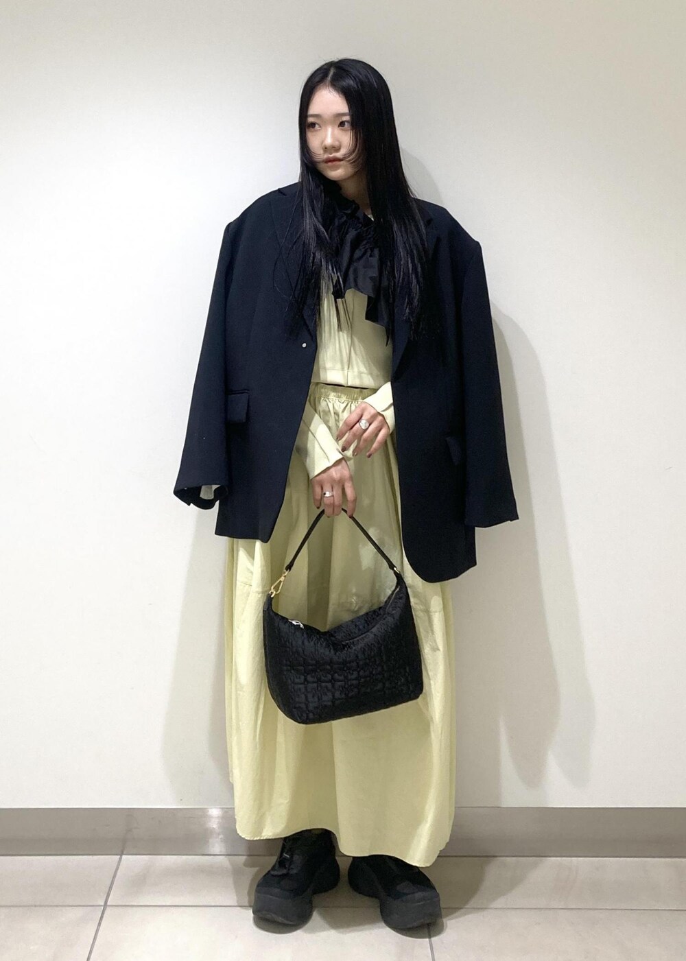 ブラック系のハンドバッグ、イエロー系のワンピース、ブラック系のワンピースを着用したレディースの冬コーディネートの2枚目の写真