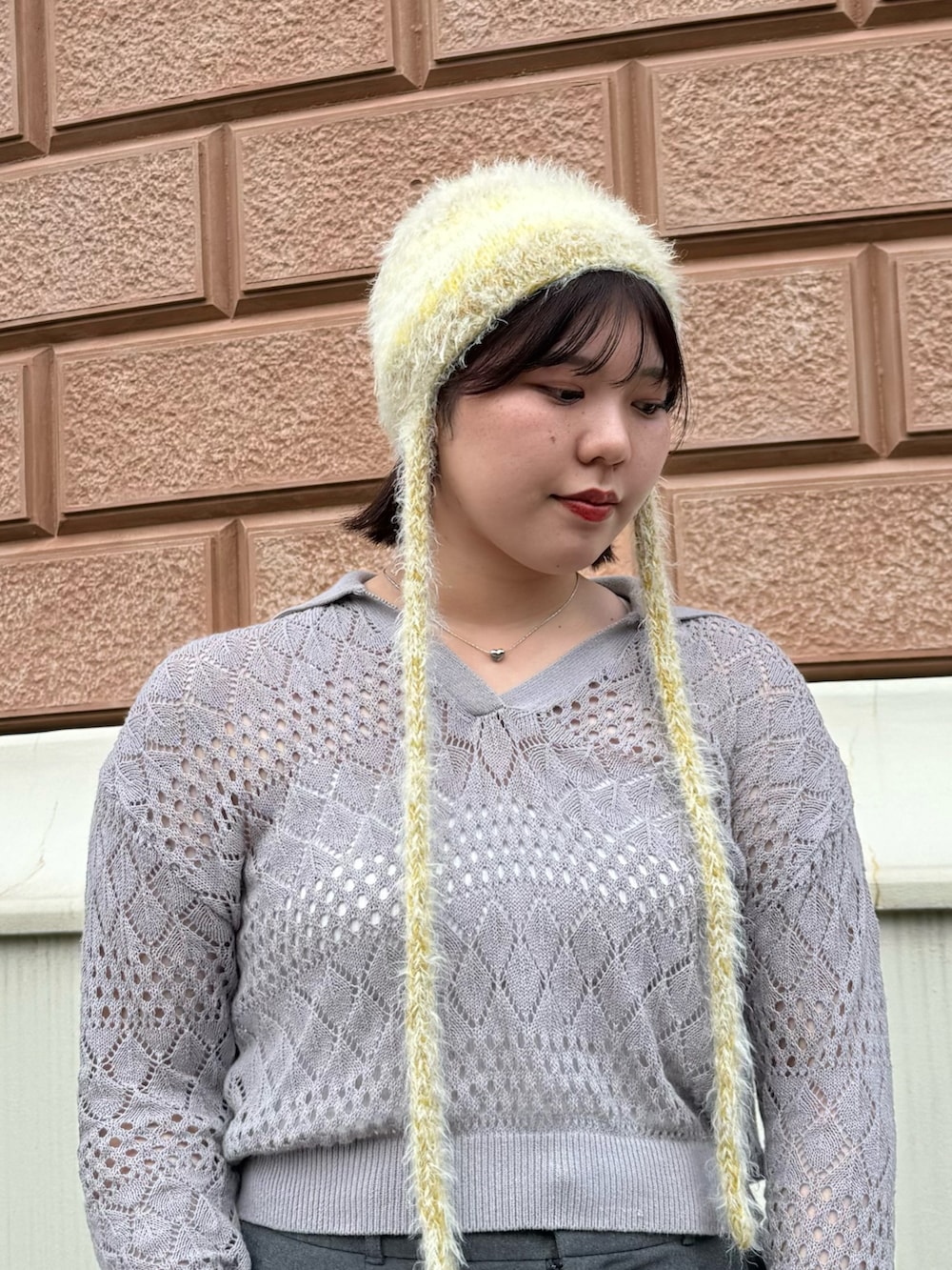 グレー系のニット/セーター、ブルー系のスニーカー、イエロー系のニットキャップ/ビーニーを着用したレディースの秋コーディネートの3枚目の写真