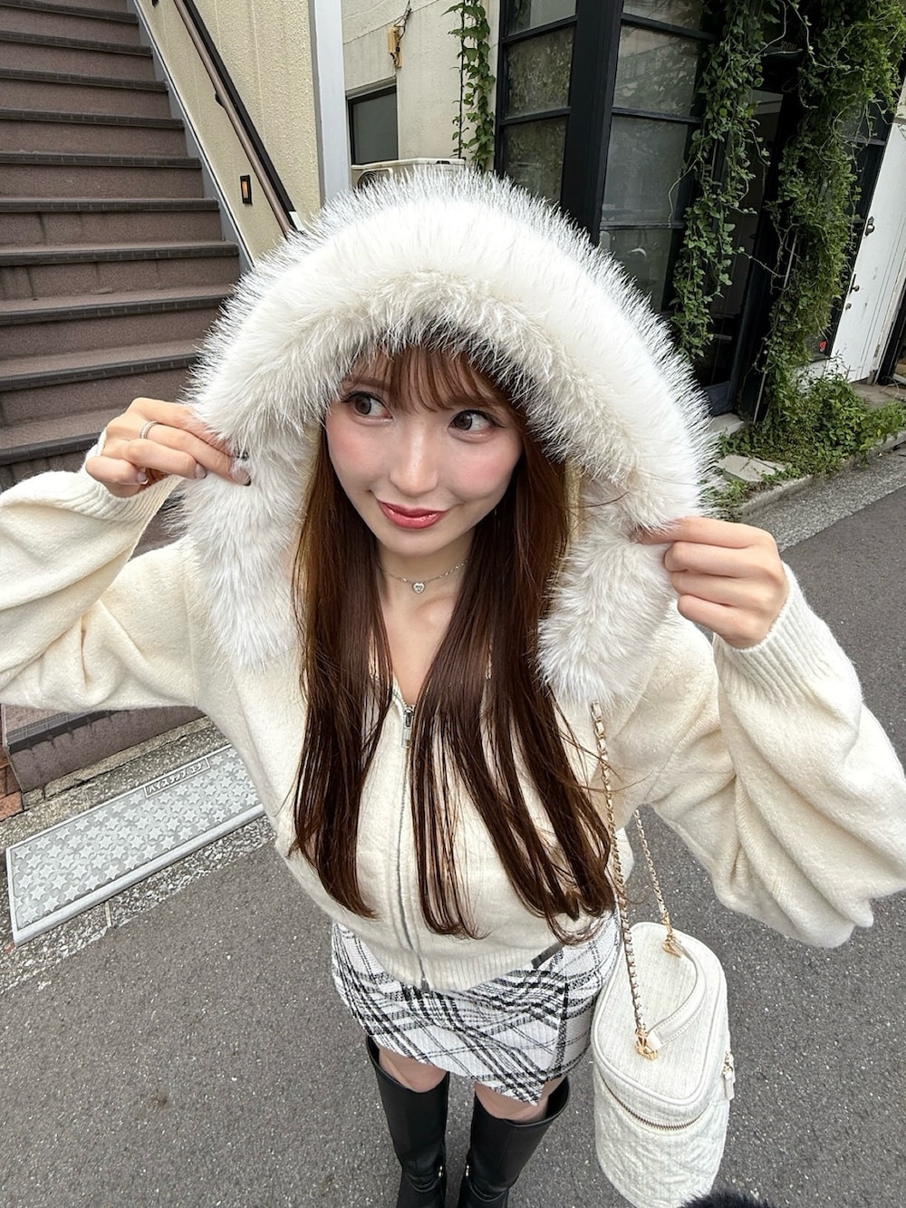 ホワイト系のスカート、ホワイト系のパーカー、ブラック系のブーツを着用したレディースの秋コーディネートの3枚目の写真