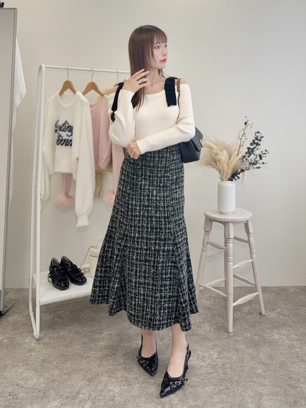 ブラック系のショルダーバッグ、ホワイト系のニット/セーター、ブラック系のスカートを着用したレディースの秋コーディネートの2枚目の写真