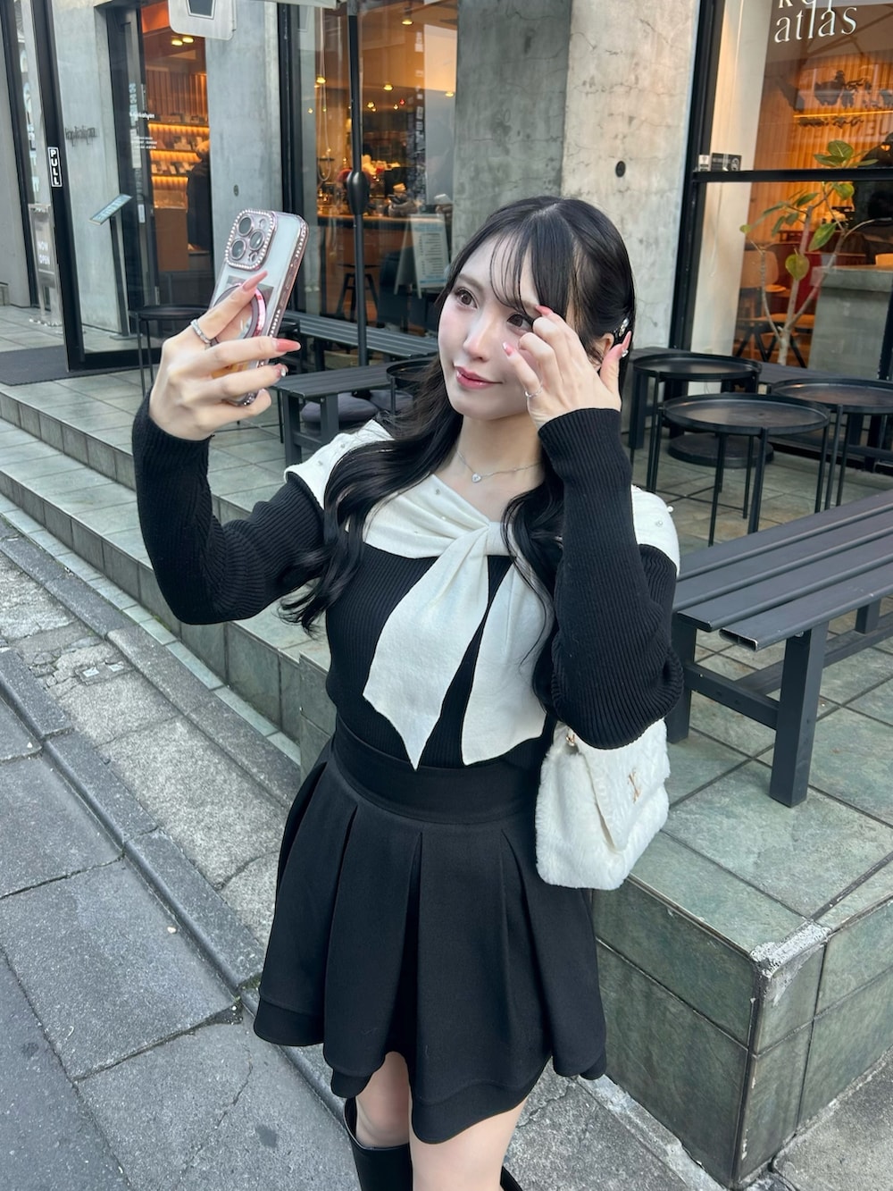 ブラック系のブーツ、ホワイト系のショルダーバッグ、ブラック系のスカートを着用したレディースの冬コーディネートの3枚目の写真