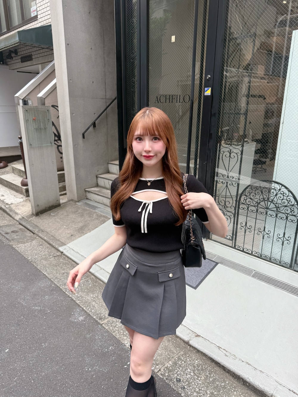 ブラック系のニット/セーター、ブラック系のパンプス、グレー系のスカートを着用したレディースの春コーディネートの3枚目の写真