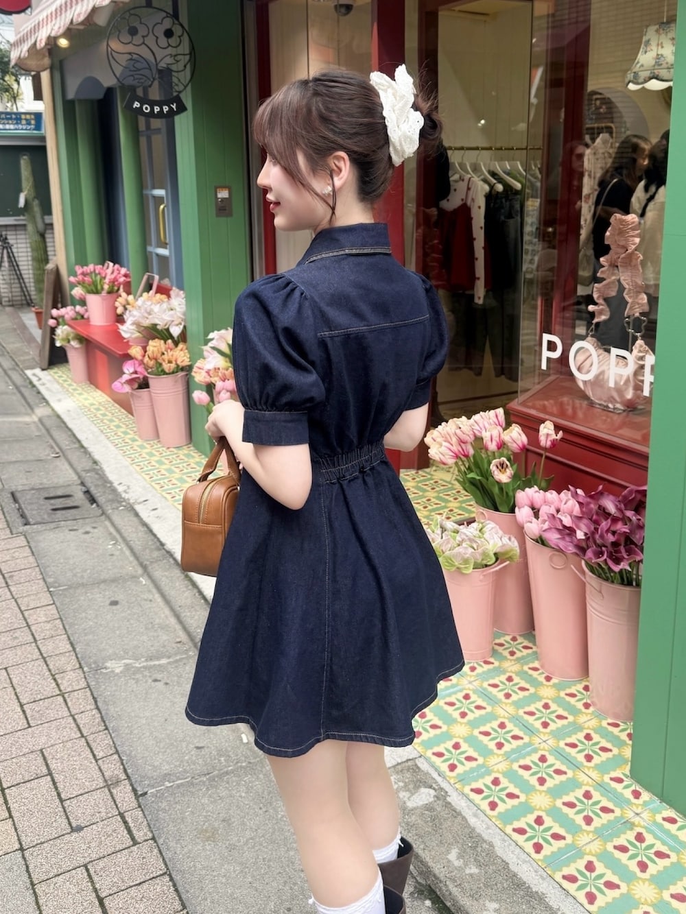 ブルー系のワンピース、ブラウン系のボストンバッグ、ブラウン系のブーツを着用したレディースの春コーディネートの2枚目の写真