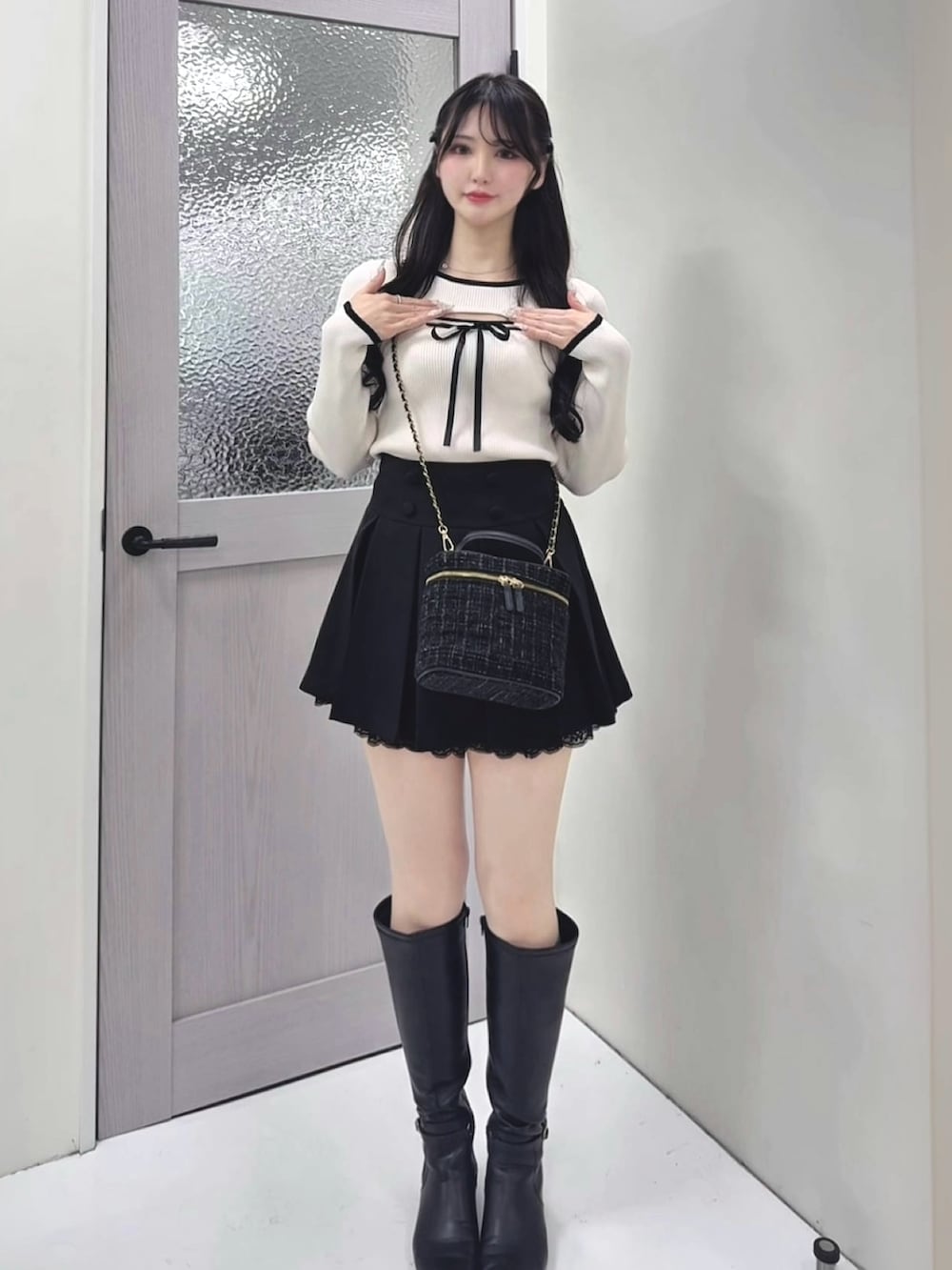 ホワイト系のニット/セーター、ブラック系のスカート、ブラック系のショルダーバッグを着用したレディースの冬コーディネートの3枚目の写真