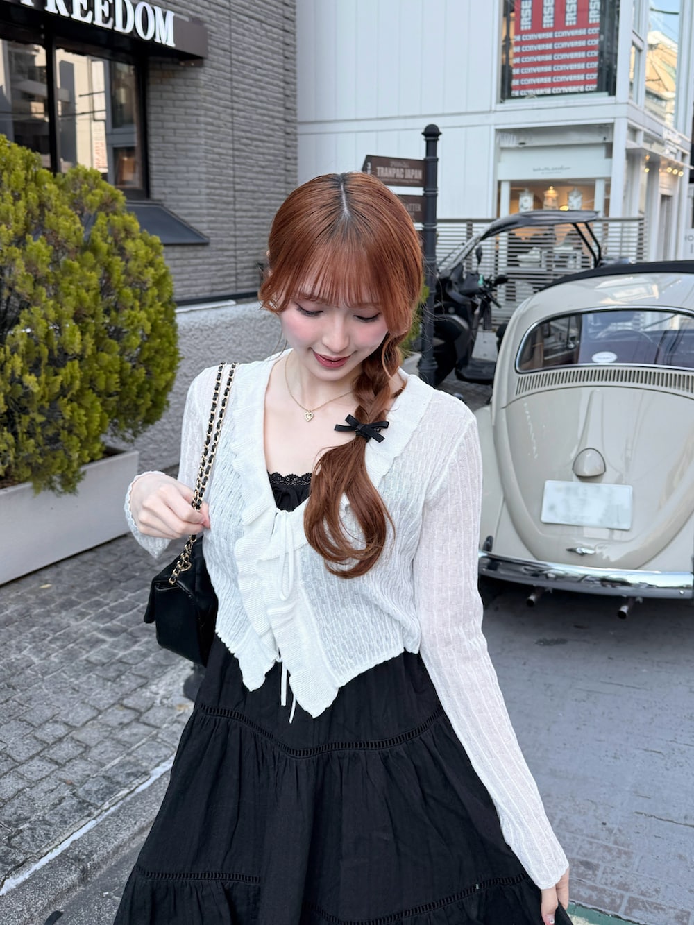 ブラック系のワンピース、ホワイト系のカーディガン/ボレロ、ブラック系のショルダーバッグを着用したレディースの春コーディネートの3枚目の写真