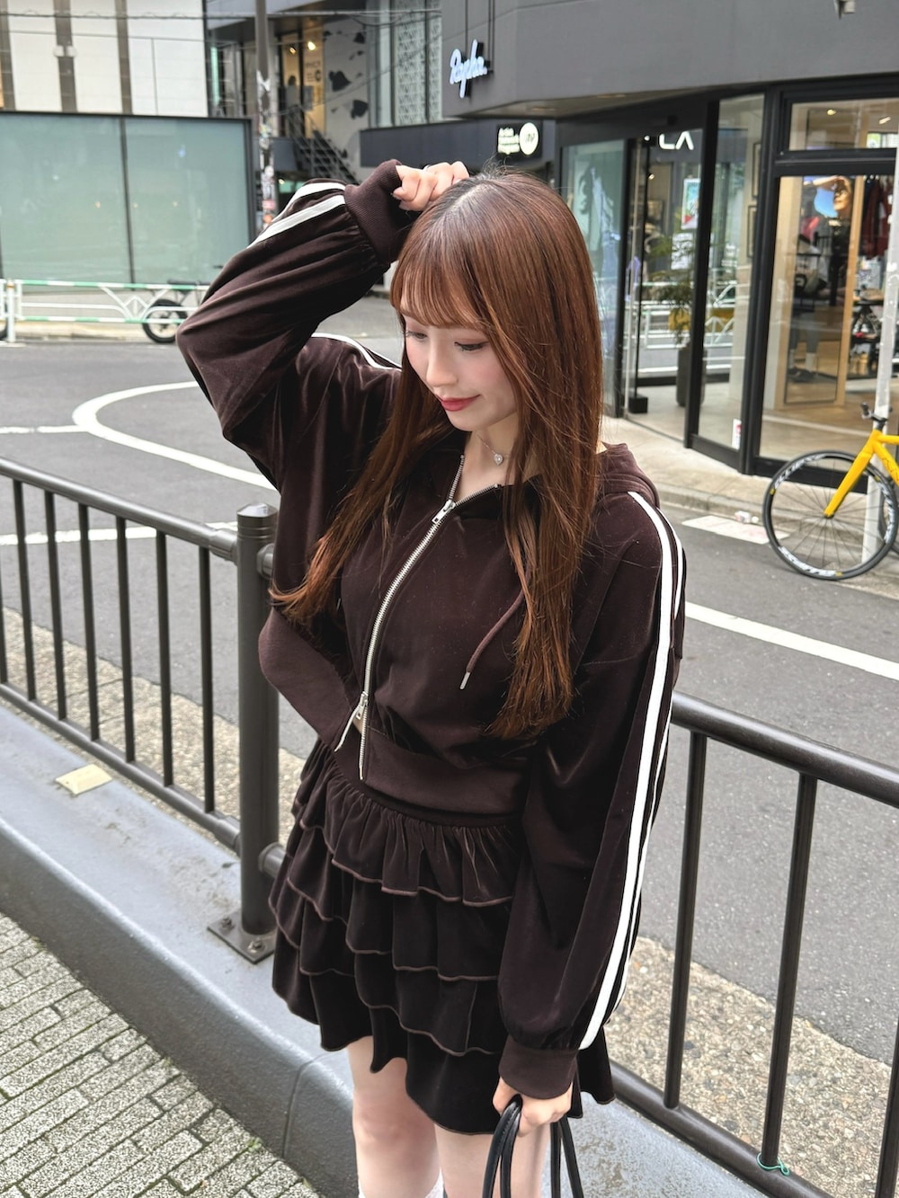 ブラウン系のスカート、ブラウン系のパーカー、ブラック系のハンドバッグを着用したレディースの秋コーディネートの5枚目の写真