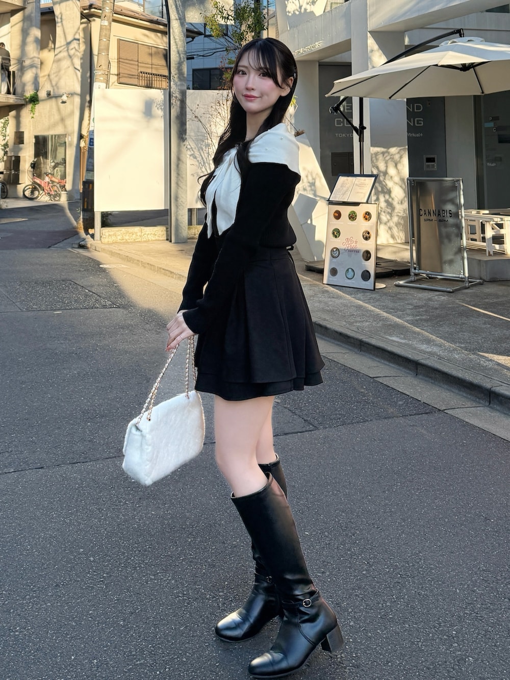 ブラック系のブーツ、ホワイト系のショルダーバッグ、ブラック系のスカートを着用したレディースの冬コーディネートの4枚目の写真