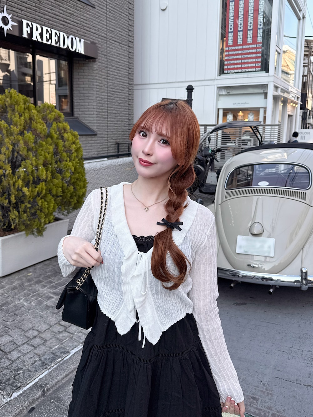 ブラック系のワンピース、ホワイト系のカーディガン/ボレロ、ブラック系のショルダーバッグを着用したレディースの春コーディネートの2枚目の写真