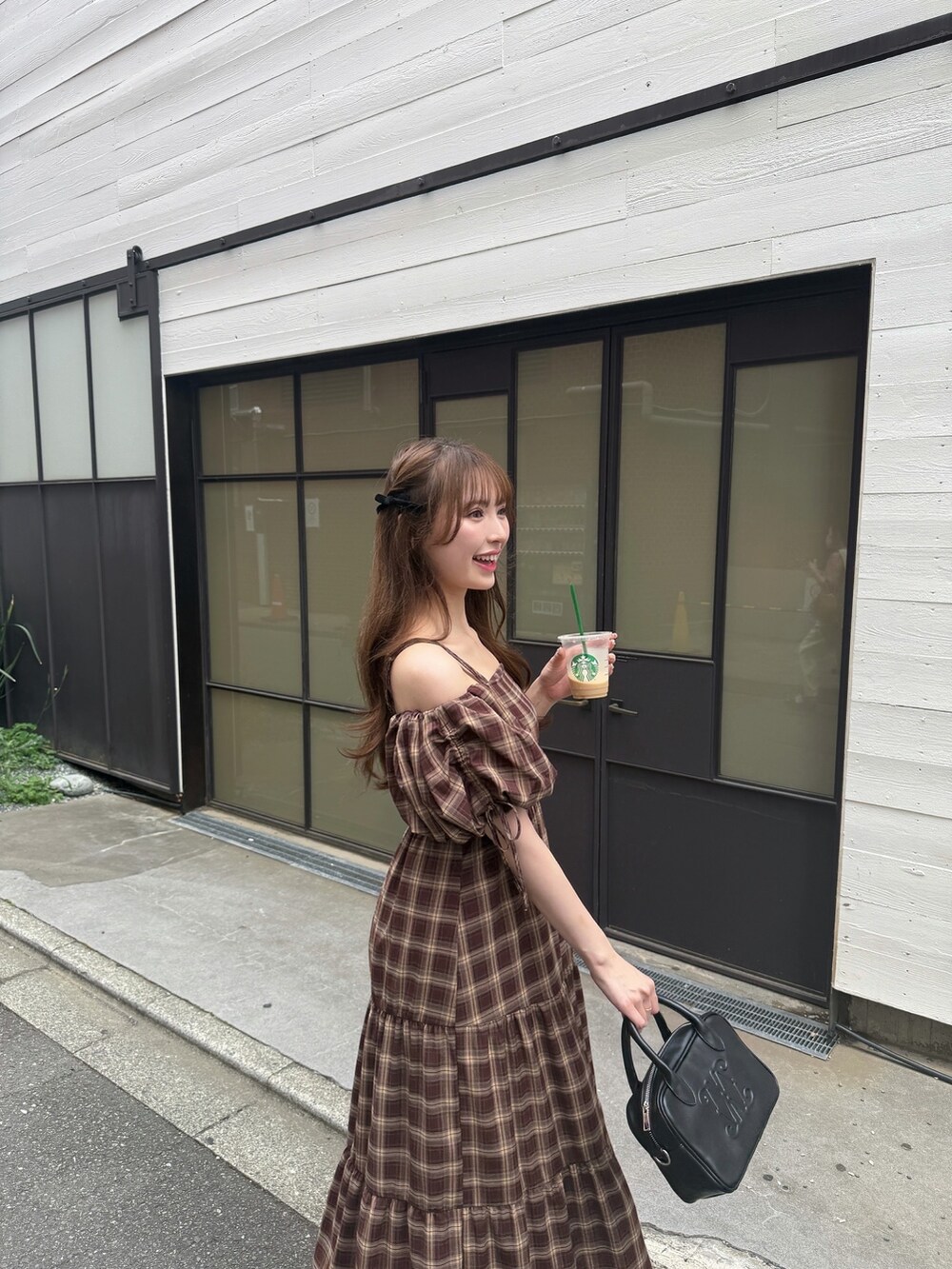 レッド系のワンピース、ブラック系のハンドバッグ、ブラック系のサンダルを着用したレディースの夏コーディネートの4枚目の写真